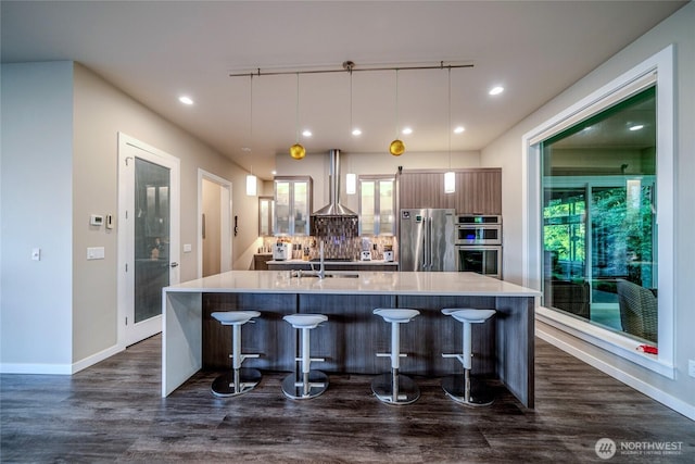5469 Wood Duck Loop, Blaine, WA 98230 - kitchen featuring stainless steel appliances, wall chimney range hood, a large island with sink, light countertops, and recessed lighting