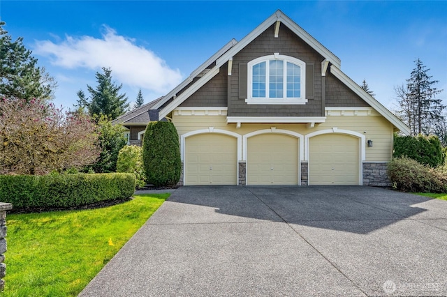craftsman house with a front lawn, stone siding, and driveway