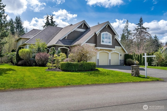 craftsman inspired home featuring stone siding, a front lawn, an attached garage, and driveway