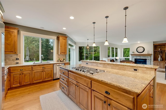 kitchen with light wood-style flooring, a sink, backsplash, and stainless steel appliances