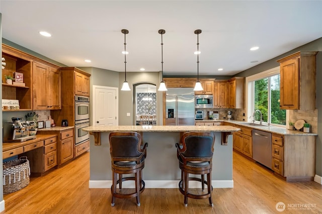 kitchen with brown cabinetry, a center island, built in appliances, and backsplash