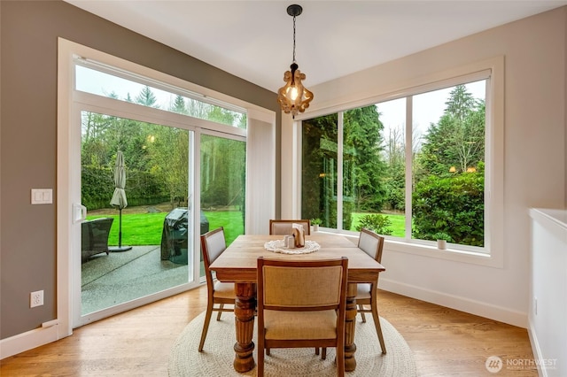 dining area with light wood-style floors, baseboards, and a healthy amount of sunlight