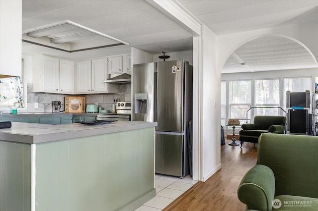 3800 Saratoga Rd, Langley, WA 98260 - kitchen featuring light countertops, white cabinetry, backsplash, stainless steel appliances, and arched walkways