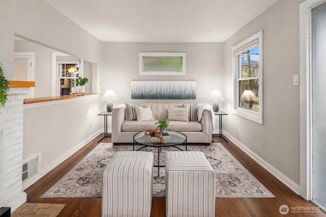 living room with visible vents, baseboards, and wood finished floors