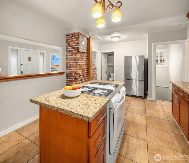 kitchen featuring freestanding refrigerator, light tile patterned floors, a kitchen island, light stone counters, and gas stove
