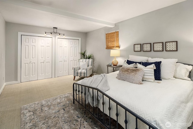 carpeted bedroom with a chandelier, baseboards, and multiple closets