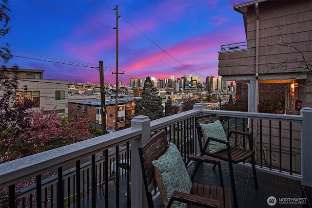 balcony at dusk featuring a city view