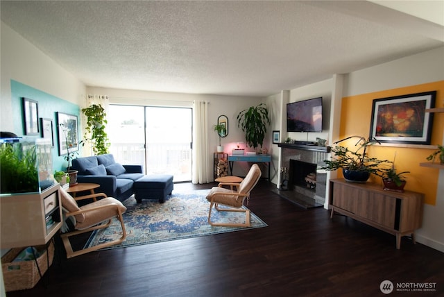 living area featuring wood finished floors, a fireplace with raised hearth, and a textured ceiling