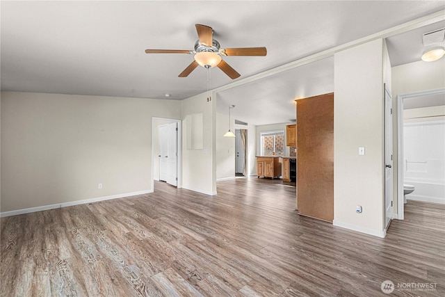 unfurnished living room with a ceiling fan, baseboards, and wood finished floors