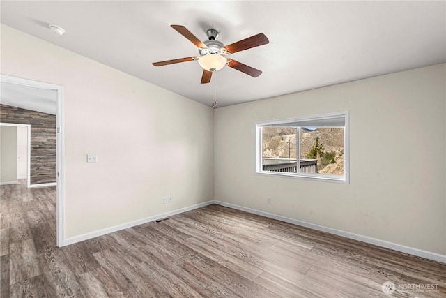 unfurnished room with baseboards, wood finished floors, and a ceiling fan