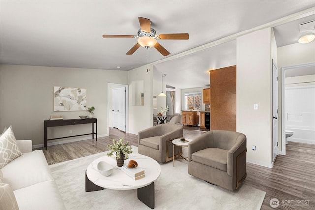 living room with baseboards, light wood-type flooring, and ceiling fan