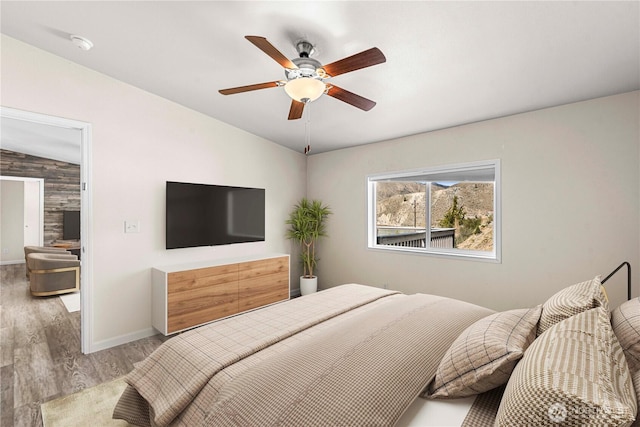 bedroom featuring baseboards, vaulted ceiling, wood finished floors, and a ceiling fan