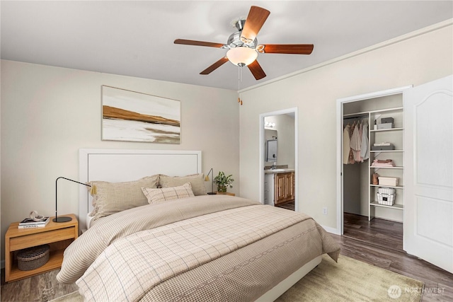 bedroom featuring a closet, connected bathroom, wood finished floors, a ceiling fan, and a walk in closet
