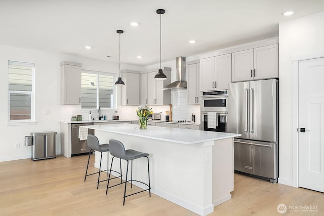 27215 106th Ave SE, Kent, WA 98030 - kitchen with light wood-style flooring, wall chimney range hood, a breakfast bar, a center island, and stainless steel appliances