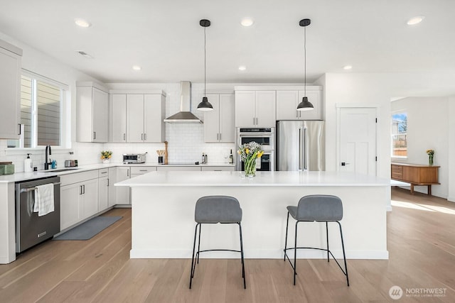 27215 106th Ave SE, Kent, WA 98030 - kitchen featuring wall chimney exhaust hood, a sink, appliances with stainless steel finishes, a kitchen bar, and a kitchen island