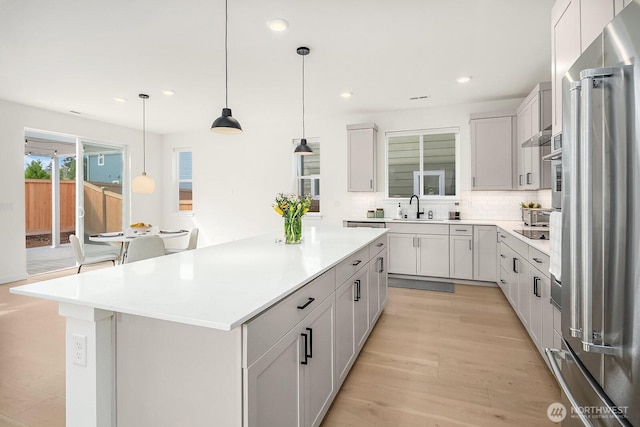 27215 106th Ave SE, Kent, WA 98030 - kitchen with tasteful backsplash, a sink, appliances with stainless steel finishes, light wood finished floors, and a kitchen island