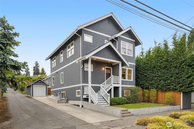 view of front of house featuring a detached garage, an outdoor structure, driveway, fence, and stairway