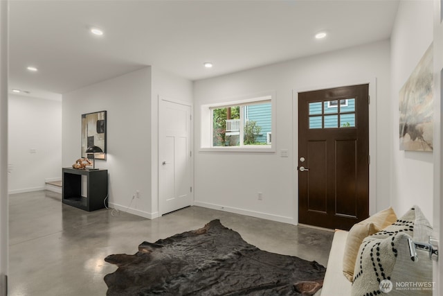 foyer entrance featuring concrete floors, baseboards, and recessed lighting