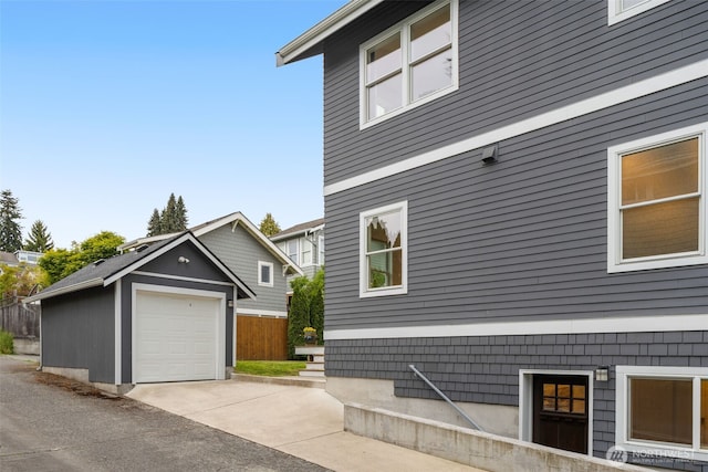 view of side of home featuring an outdoor structure, a garage, and driveway