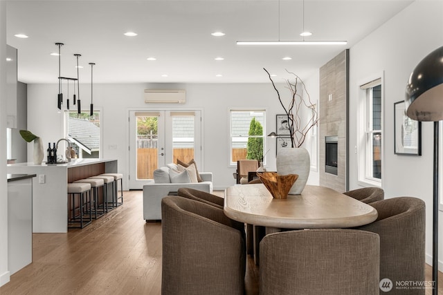 dining room with a wall unit AC, light wood finished floors, a fireplace, and recessed lighting