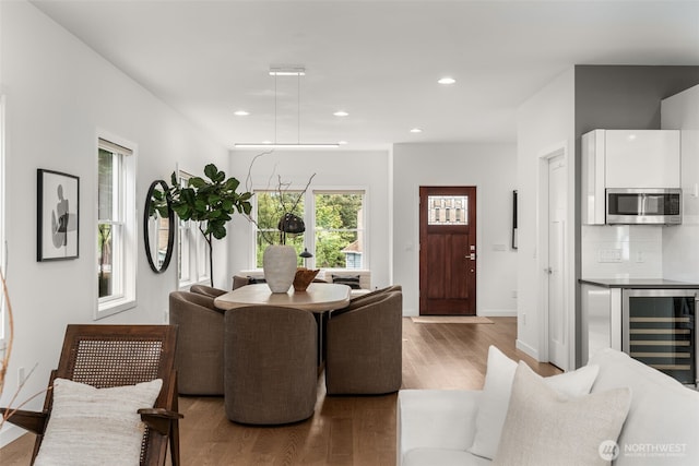living area with beverage cooler, wood finished floors, recessed lighting, and baseboards