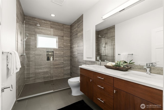 full bathroom with a tile shower, double vanity, toilet, and tile patterned floors