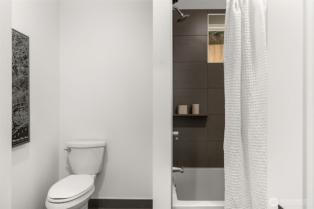 full bath with toilet, baseboards, and shower / tub combo