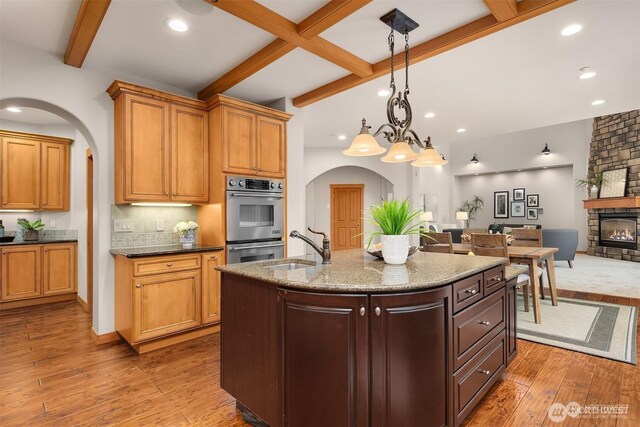 25935 SE 235th Way, Maple Valley, WA 98038 - kitchen featuring a sink, wood-type flooring, arched walkways, and stainless steel double oven