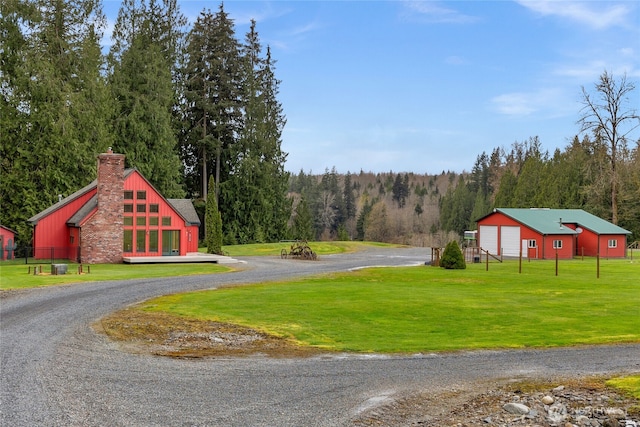view of road with a wooded view, a pole building, and driveway