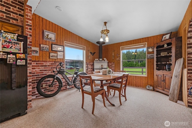 carpeted dining area featuring wood walls and a wood stove