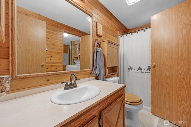 bathroom featuring vanity, toilet, curtained shower, wood walls, and washer and clothes dryer