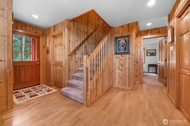 foyer featuring wood walls, recessed lighting, stairway, and light wood-type flooring