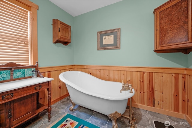 bathroom featuring a freestanding tub and a wainscoted wall