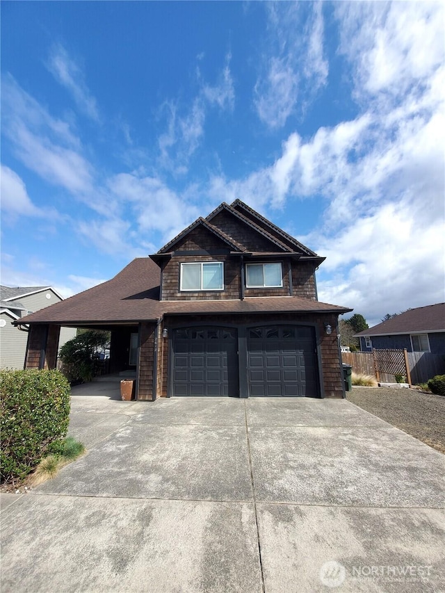 view of front of house with driveway, a garage, and fence