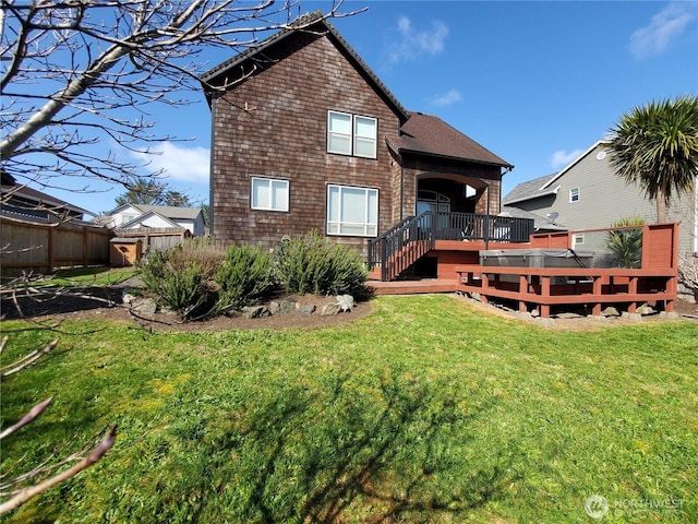 rear view of property with a lawn, fence, and a deck