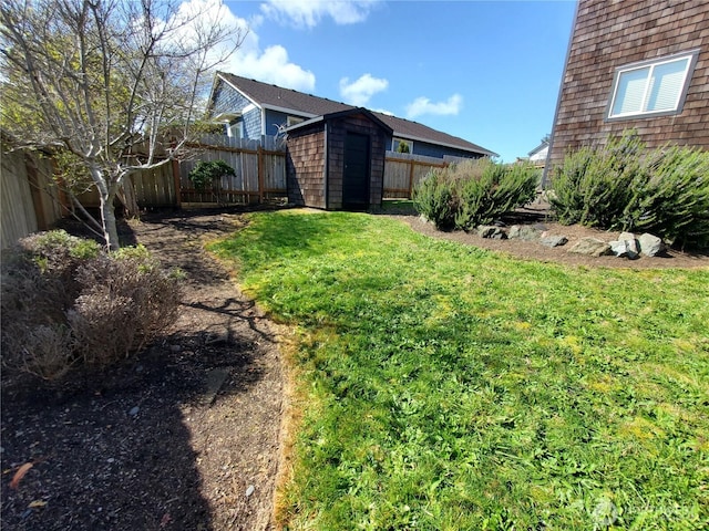 view of yard with a fenced backyard, an outdoor structure, and a storage shed