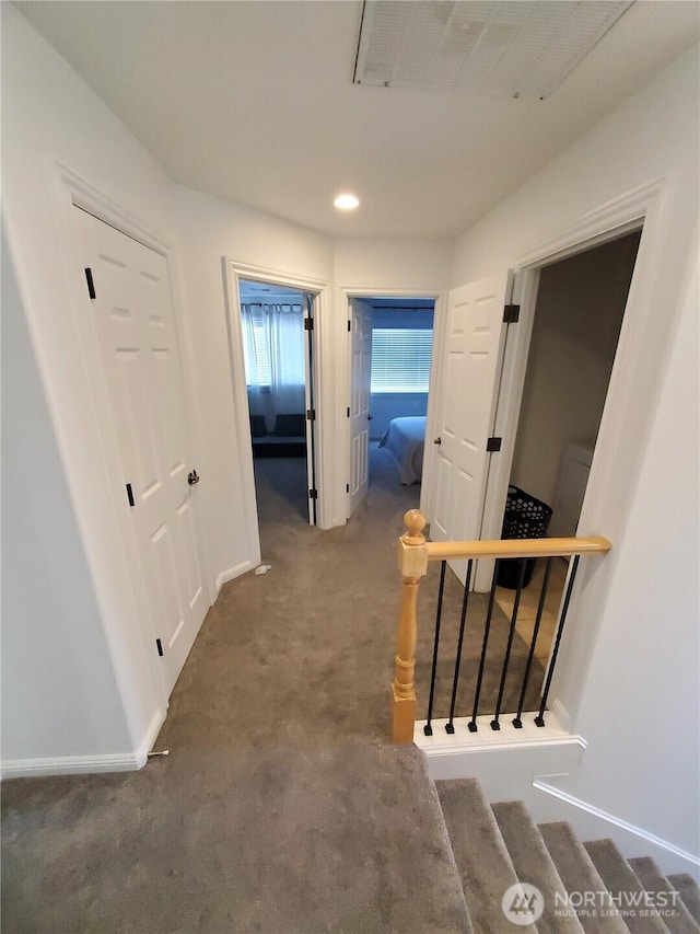 hallway featuring baseboards, visible vents, stairway, and carpet
