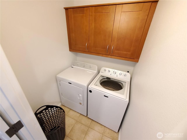 laundry area with light tile patterned floors, cabinet space, and washer and dryer