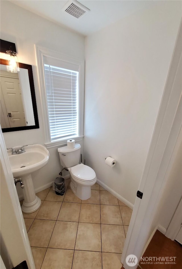 bathroom featuring baseboards, visible vents, toilet, and tile patterned flooring