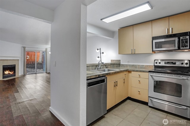 12519 SE 41st Pl Unit B103, Bellevue, WA 98006 - kitchen with open floor plan, cream cabinetry, stainless steel appliances, a tile fireplace, and a sink
