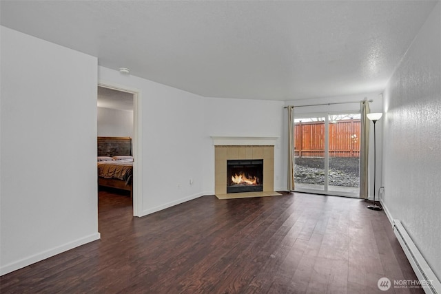 12519 SE 41st Pl Unit B103, Bellevue, WA 98006 - unfurnished living room with a tiled fireplace, a baseboard radiator, baseboards, and wood finished floors