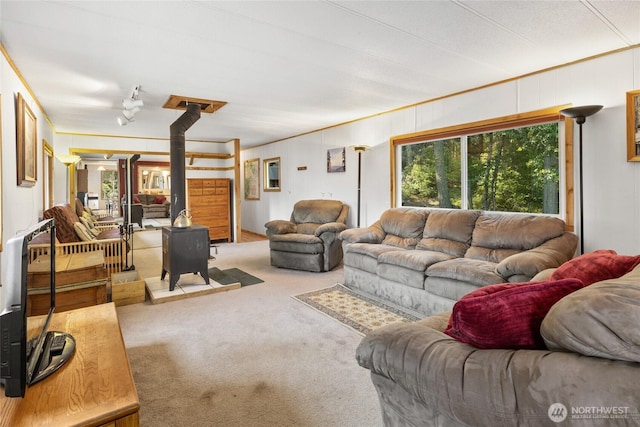 living room featuring ornamental molding, carpet, and a wood stove