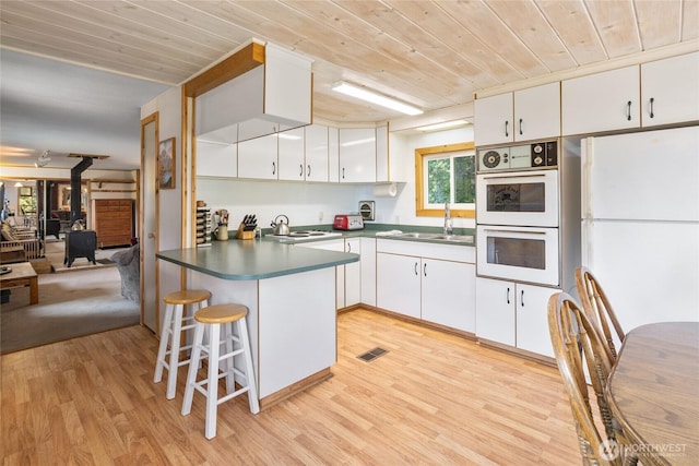 kitchen with white appliances, visible vents, wooden ceiling, and a peninsula