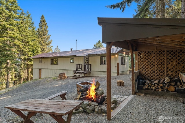 rear view of house with an outdoor fire pit and metal roof