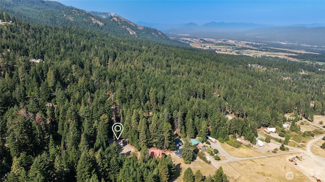 birds eye view of property featuring a wooded view and a mountain view