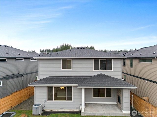back of property with central AC, a fenced backyard, a patio area, and roof with shingles