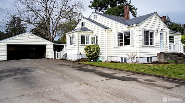 view of side of property featuring a chimney, a garage, and an outbuilding