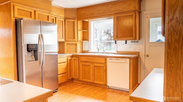 kitchen featuring stainless steel refrigerator with ice dispenser, white dishwasher, a sink, light countertops, and light wood-style flooring