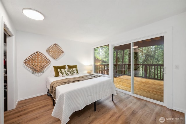 bedroom featuring baseboards, wood finished floors, and access to exterior