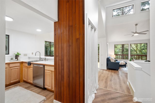 bar with a high ceiling, a sink, light wood finished floors, a ceiling fan, and stainless steel dishwasher